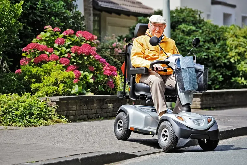 Ein älterer Herr fährt mit einem Elektromobil auf dem Gehweg